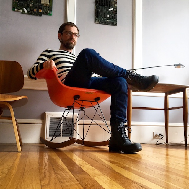 Joey sitting in orange Eames RAR rocker